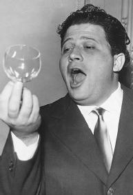 INTHIS 1957 PHOTOGRAPH, ITALIAN OPERA SINGER LUIGI INFANTINO TRIES TO BREAK A WINE GLASS BY SINGING A HIGH "C" NOTE. CONTRARY TO POPULAR BELIEF, THE NOTE DOES NOT HAVE TO BE A PARTICULARLY HIGH ONE TO BREAK THE GLASS: RATHER, THE NOTE SHOULD BE ON THE SAME WAVELENGTH AS THE GLASS'S OWN VIBRATIONS. WHEN THIS OCCURS, SOUND ENERGY IS TRANSFERRED DIRECTLY TO THE GLASS, WHICH IS SHATTERED BY THIS SUDDEN NET INTAKE OF ENERGY. (Hulton-Deutsch Collection/Corbis. Reproduced by permission.)