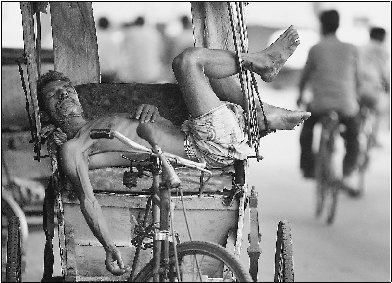 An Indian rickshaw driver naps in the shade to escape a heat wave in Calcutta in 2002. Tropical areas may suffer most from global warming.