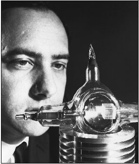 Dr. Theodore Maiman, creator of the first successful laser, examines an early version of the device. The cube inside is the ruby crystal that emitted the laser beam.