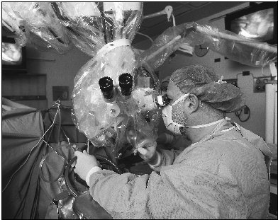 A doctor removes a brain tumor by aiming a laser beam at the tumor. The exposed brain is visible on surrounding monitor screens.