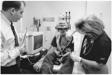 A young patient diverts his attention away from a painful medical treatment by becoming absorbed in a virtual reality program.